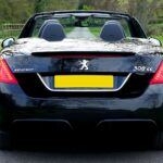 Czarny kabriolet na wiejskiej drodze latem, widok od tyłu