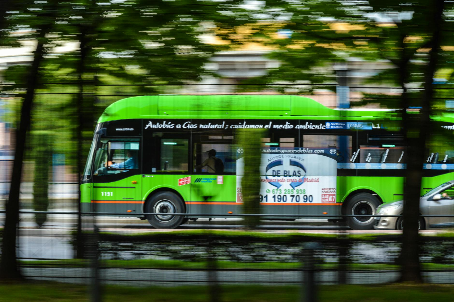 Zielony autobus na gaz ziemny jedzie ulicą w centrum miasta