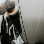 Polerowanie czarnego Fiata maszyną polerską z bliska