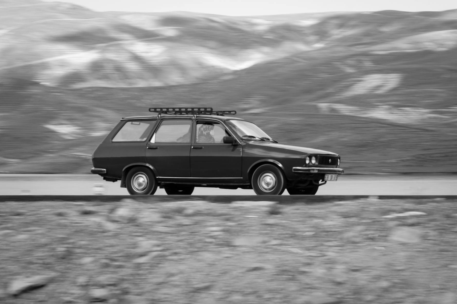 Czarno-biała Mazda kombi jadąca górską drogą