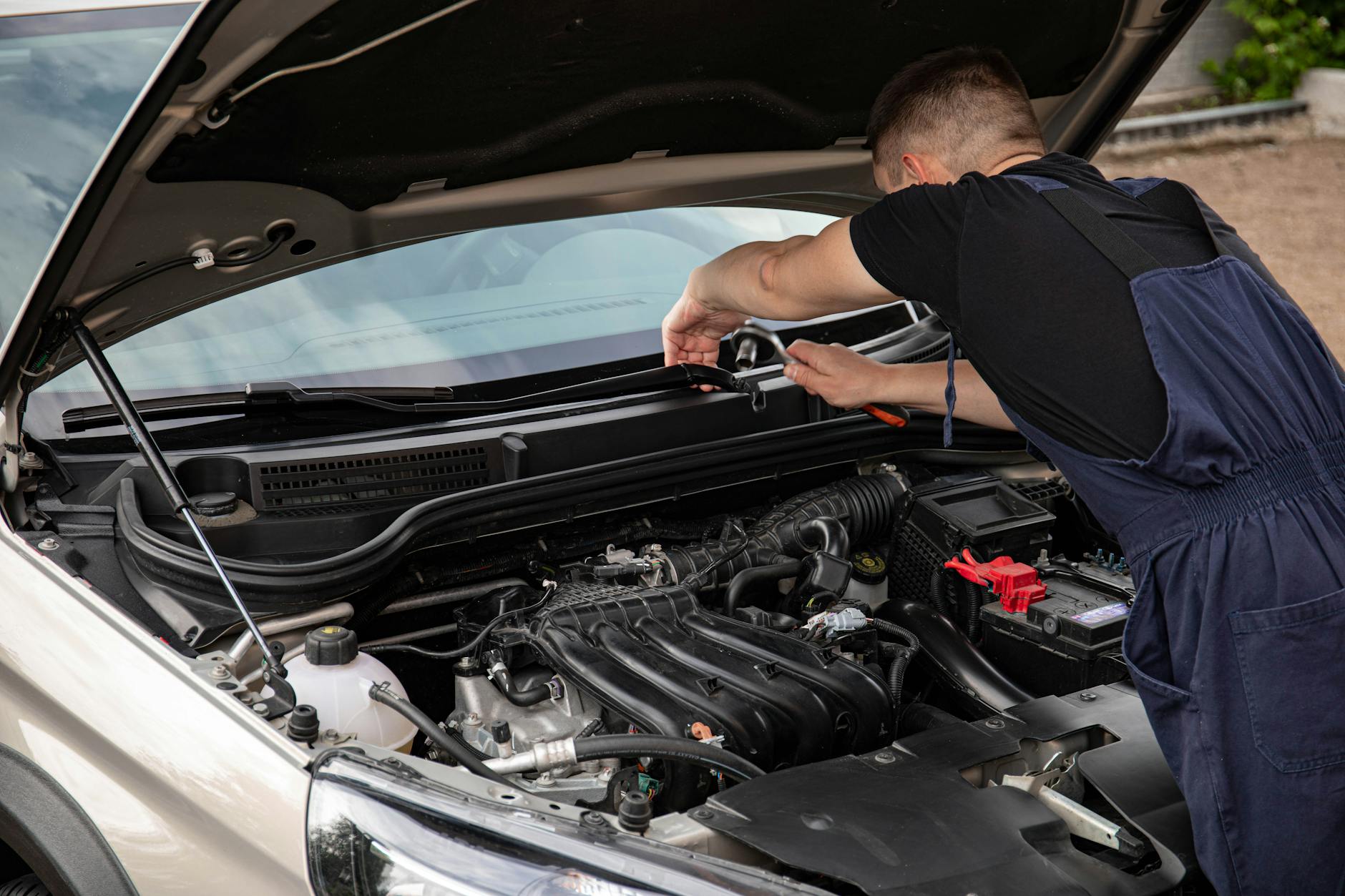 Mechanik naprawiający silnik samochodu na zewnątrz w dzień Mechanik naprawiający silnik samochodu na zewnątrz w dzień