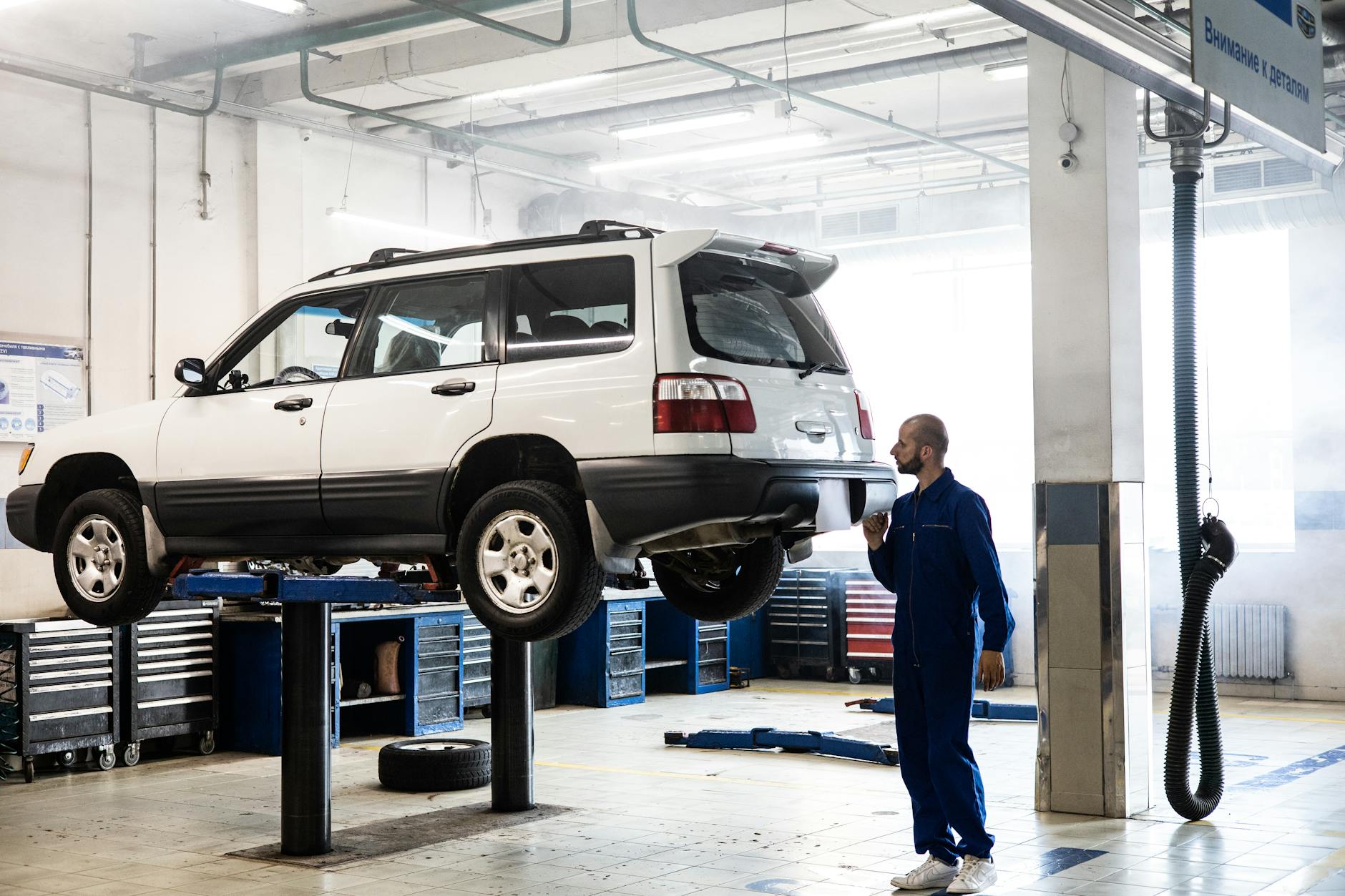 Mechanik ogląda podwozie podniesionego Volvo XC60 w warsztacie Mechanik ogląda podwozie podniesionego Volvo XC60 w warsztacie