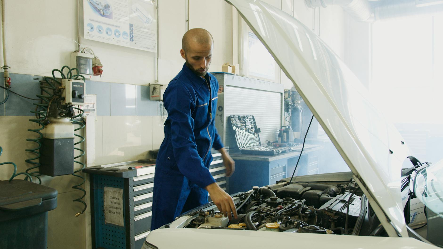 Mechanik w niebieskim kombinezonie sprawdza silnik Maserati w warsztacie