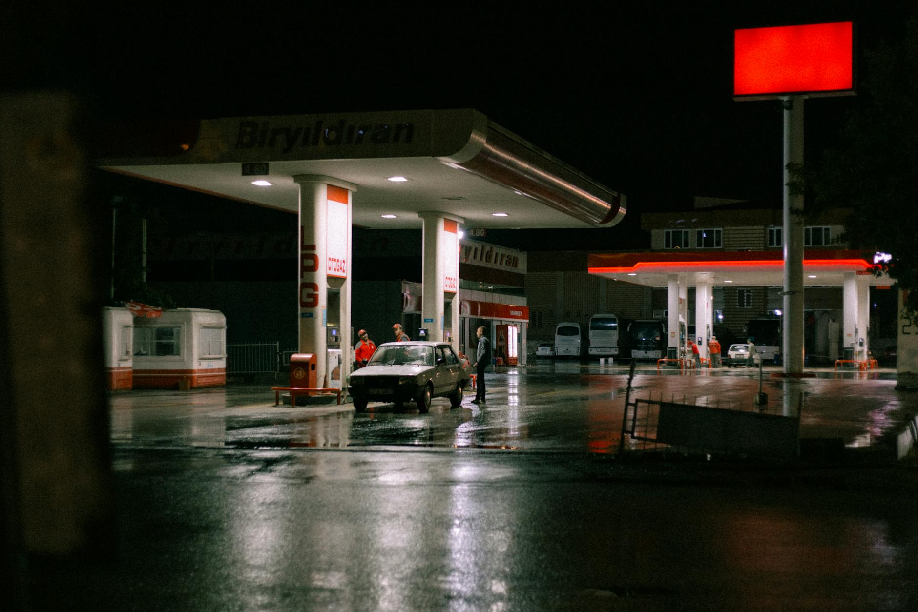 Volvo tankujące paliwo na jasno oświetlonej stacji nocą Volvo tankujące paliwo na jasno oświetlonej stacji nocą