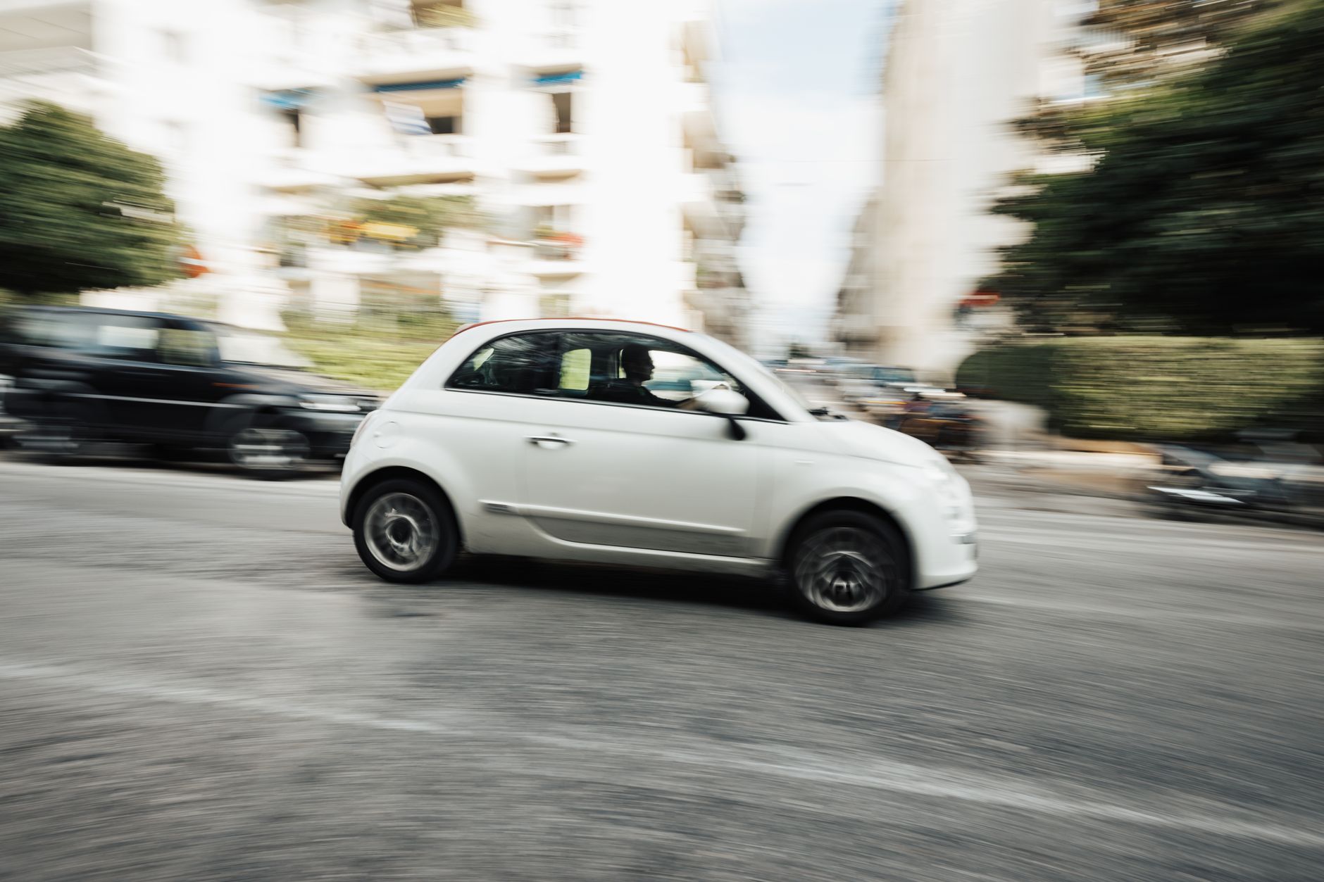 Biała Dacia Sandero jedzie szybko ulicą w centrum miasta