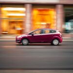 Dacia Sandero LPG czy benzyna – który napęd wybrać do miasta Czerwone Dacia Sandero jedzie dynamicznie ulicą w centrum miasta