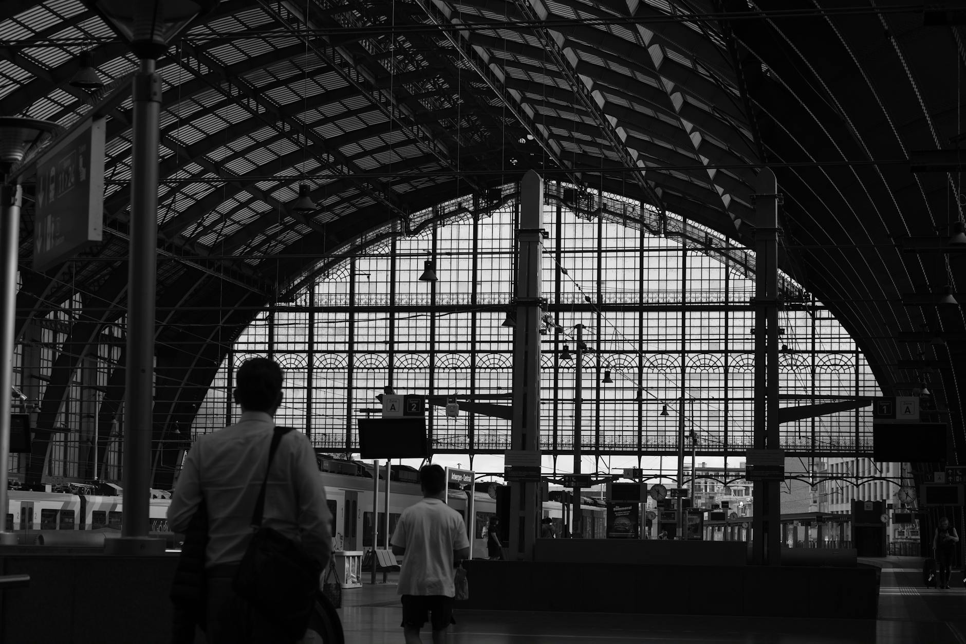 Wnętrze dworca Antwerpia Centralna w czerni i bieli z sylwetkami podróżnych