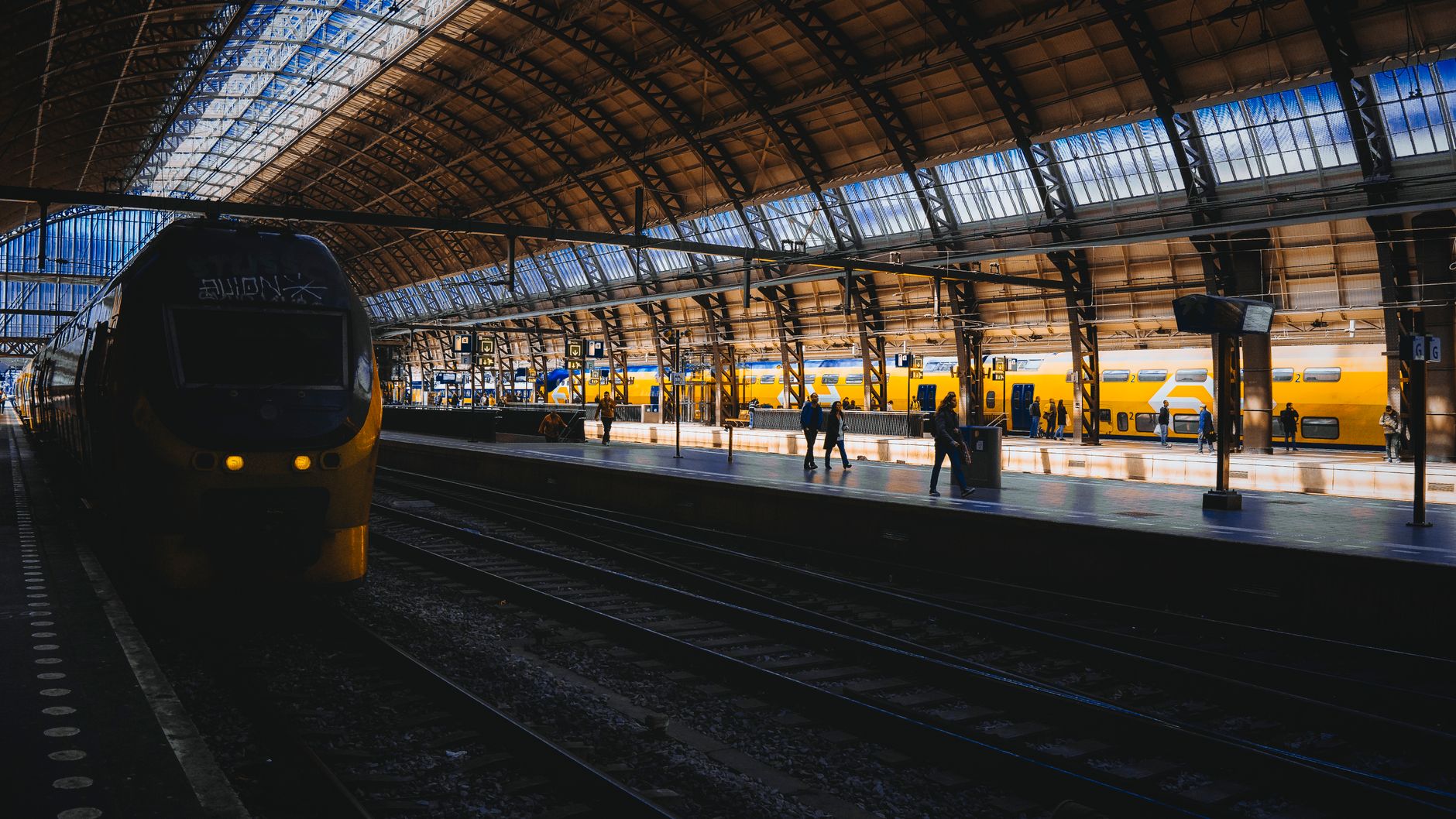 Żółte pociągi na tle zabytkowego dworca Amsterdam Centraal