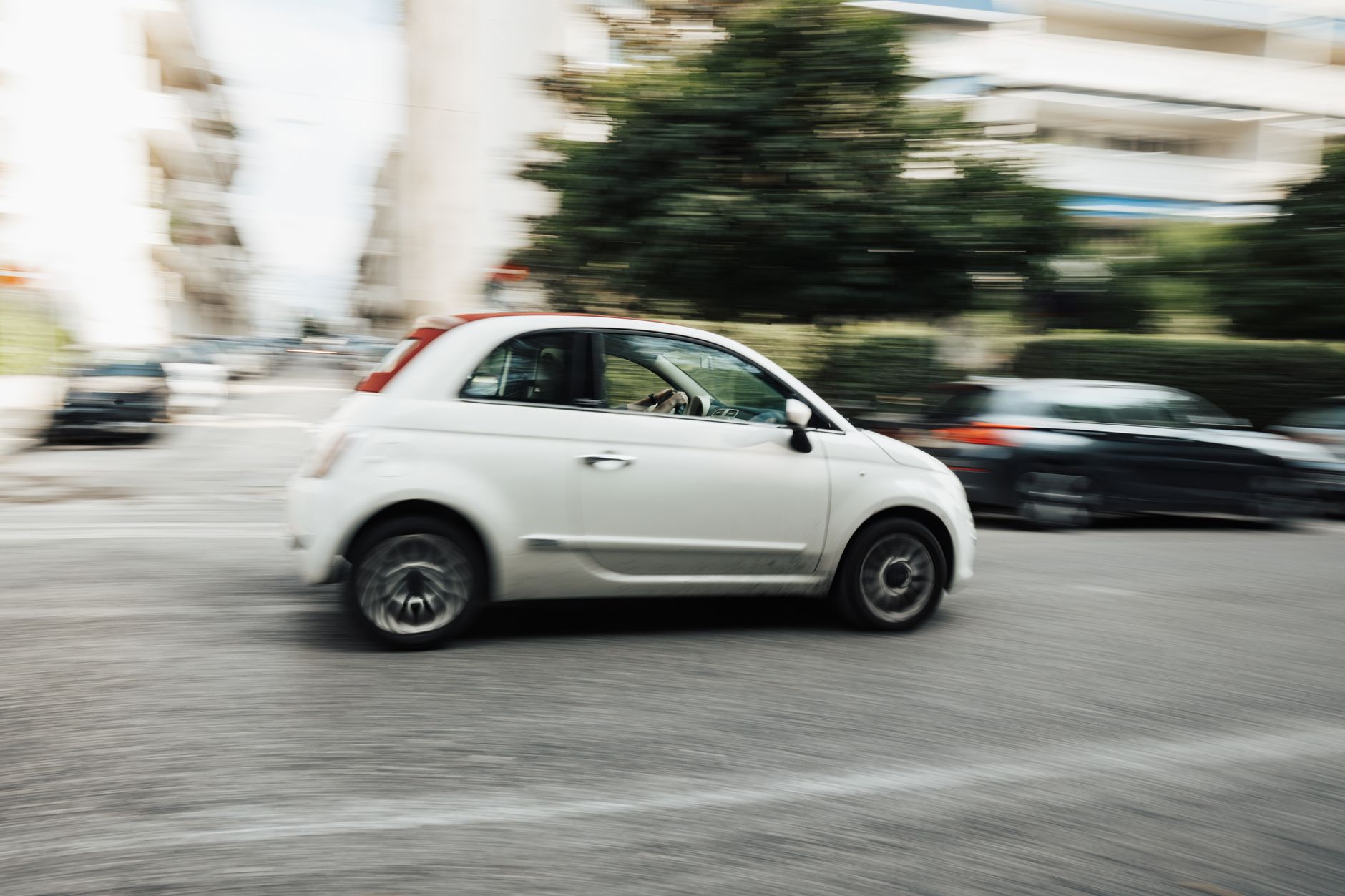 Białe miejskie auto Mitsubishi jedzie szybko po ulicy w centrum miasta