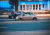 Mitsubishi Space Star jako miejskie auto z importu czy to się w ogóle opłaca Fiat 500 jedzie nocą obok nowoczesnego, niebiesko podświetlonego budynku