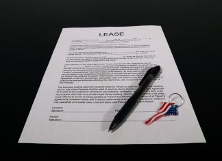 Zakup Geely na firmę leasing czy wynajem długoterminowy które finansowanie wybrać Dokument umowy leasingu z długopisem i brelokiem z flagą USA na stole
